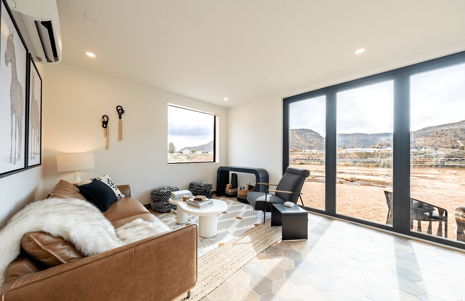 Modern living room interior with leather sofa, decorative pillows, and stylish furniture, featuring large windows showcasing a scenic outdoor view, emphasizing thoughtful design and quality craftsmanship by Oak-n-Crete.